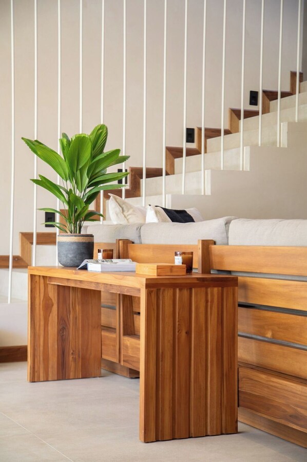 A modern living room with a wooden bench, a potted plant, and a staircase in the background. - Villa Lapa, Villa Lapa (Sámara)