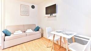 Una habitación moderna con sofá, mesa de comedor y televisor de pantalla plana en la pared.