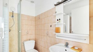 Une salle de bain avec des toilettes, un lavabo et une douche.