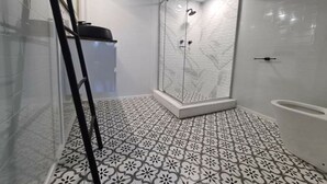 A modern bathroom with a glass-enclosed shower, patterned floor tiles, and a white toilet. - away on holiday (Terrigal)