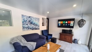 A modern living room with a blue sofa, a wooden coffee table, and a flat-screen TV mounted on the wall. - away on holiday (Terrigal)