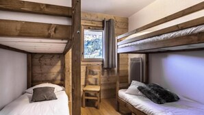 A compact room with bunk beds, a small wooden chair, and a window with a view of a mountainous landscape. - Valmogrange E4 - 8 Persons - Luxury Apartment on the Piste (Les Avanchers-Valmorel)