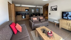 A modern living room with a grey sofa, a wooden coffee table, and a TV. - Valmogrange E4 - 8 Persons - Luxury Apartment on the Piste (Les Avanchers-Valmorel)