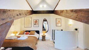 A bedroom with a large bed, a bedside table, a mirror, and a radiator. - Charming Duplex in Marais for 2 People (Paris)
