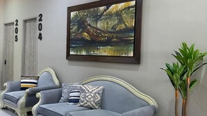 A modern living room with a grey sofa set, a large framed painting, and a potted plant. - Hotel Panorama  (El Banco)