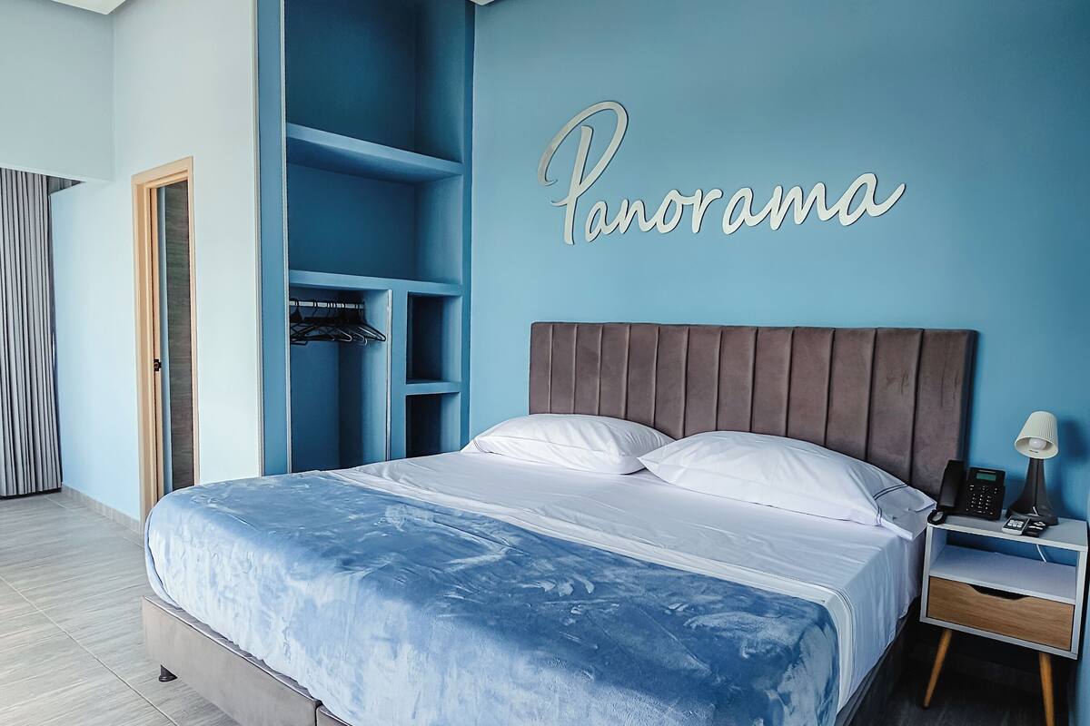 Un dormitorio con cama, mesita de noche, armario y una pared con la palabra "Panorama".