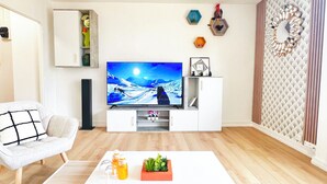 Un salon moderne doté d’un téléviseur à écran plat, de meubles blancs et d’œuvres d’art décoratives murales.