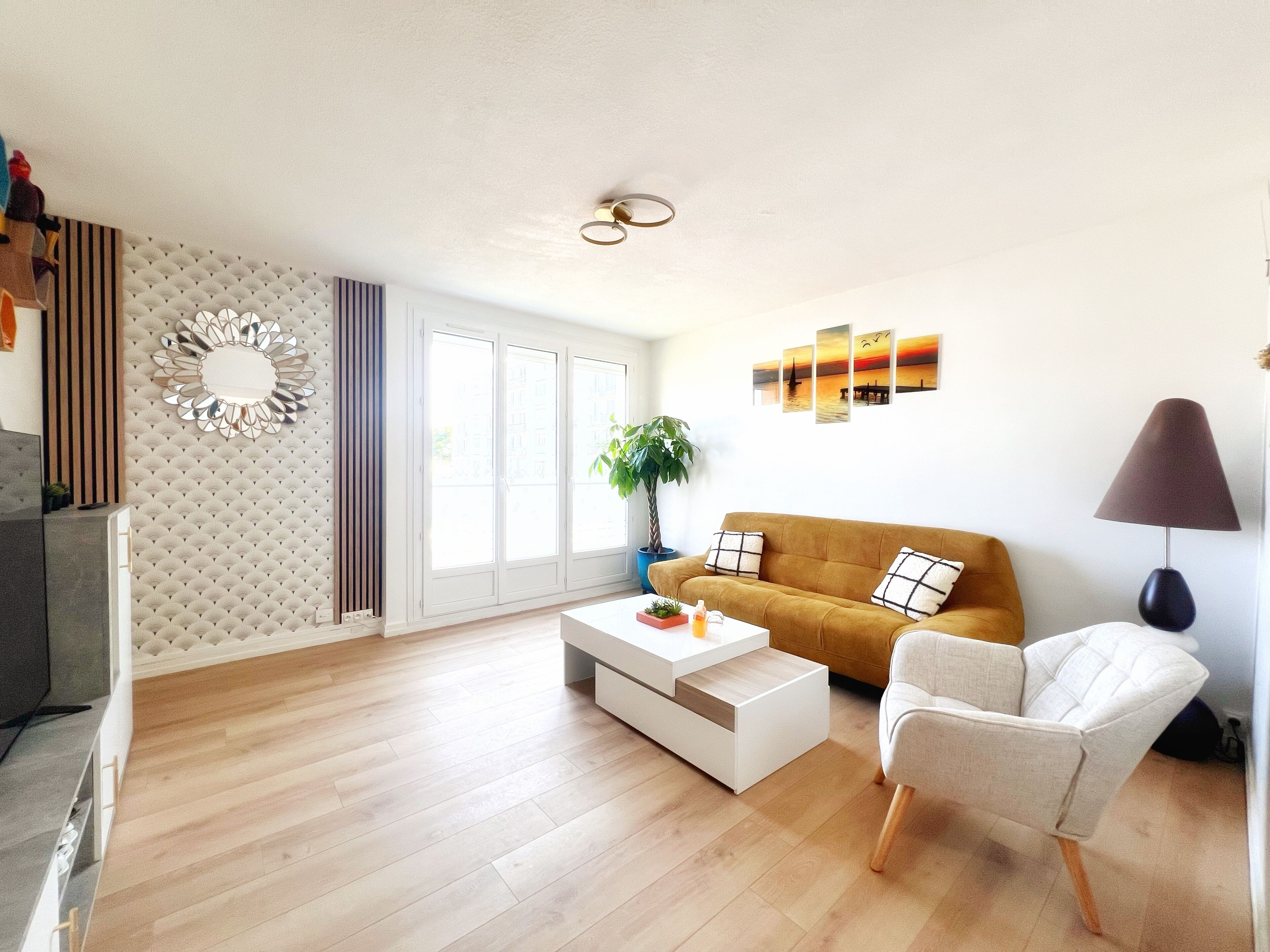 A modern living room with a sofa, a chair, a coffee table, and a lamp. There is a large window with a view of the outside.