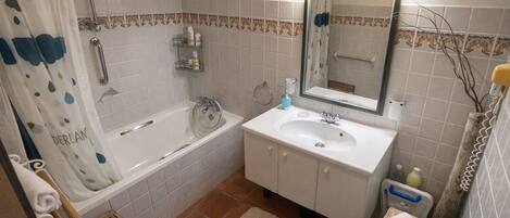 A bathroom with a bathtub, a sink, a mirror, and a shower curtain.