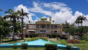 A large resort with a swimming pool, palm trees, and a multi-story building. - Anse des Rochers Beach & Pool Resort (Saint-François)