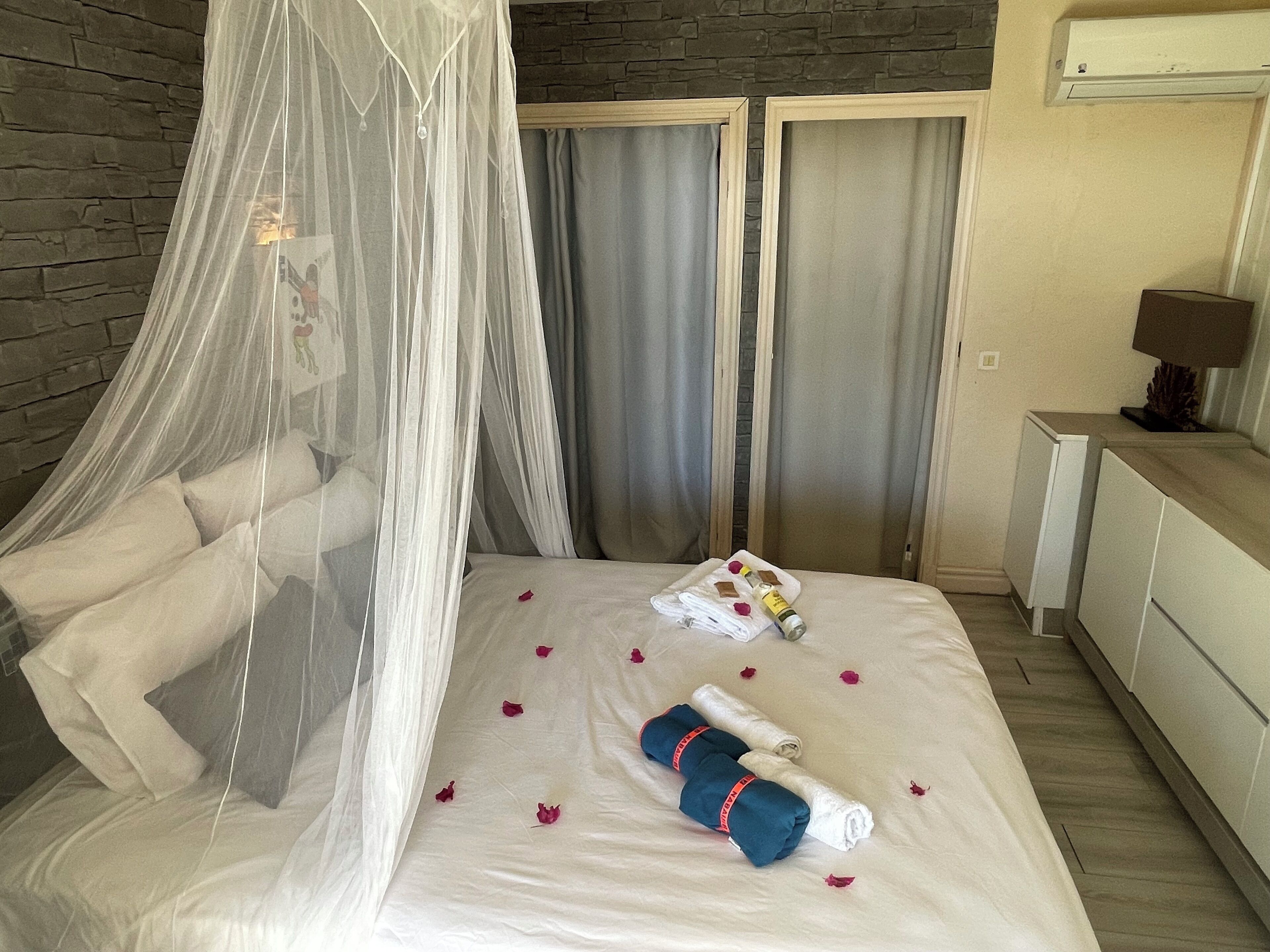 Un lit bien fait, agrémenté d’un dais, de serviettes et de pétales de rose.