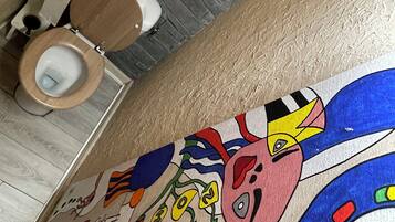 A bathroom with a wooden toilet, a tiled floor, and a colorful mural on the wall.