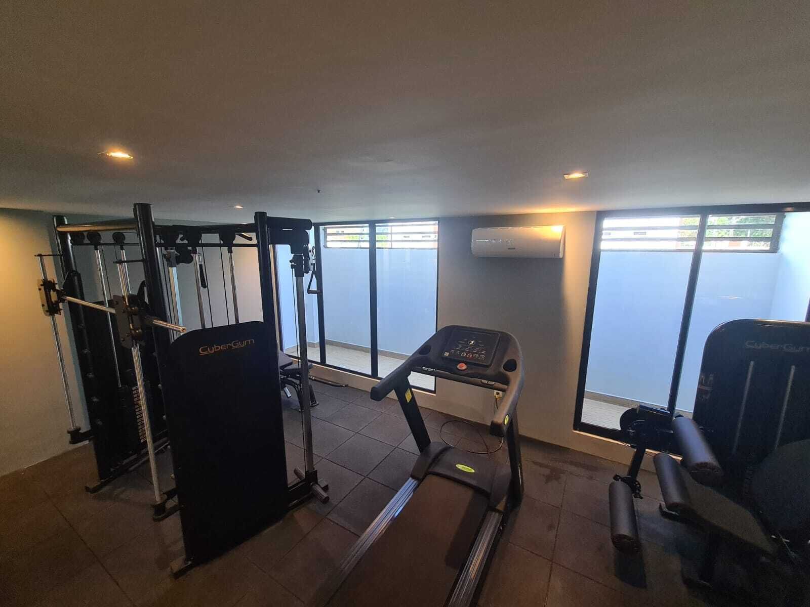 A gym with a treadmill, weight machines, and a pull-up bar area.