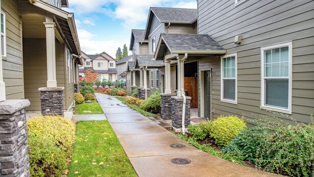 A row of townhouses with a paved walkway, stone pillars, and well-maintained landscaping. - TWO townhomes for your giant group! (Corvallis)