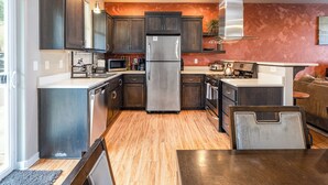 A modern kitchen with dark wood cabinets, stainless steel appliances, and a wooden floor. - TWO townhomes for your giant group! (Corvallis)