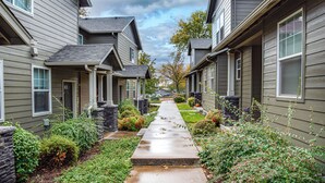 A residential street with houses having a uniform architectural style, a clear sidewalk, and well-maintained landscaping. - TWO townhomes for your giant group! (Corvallis)