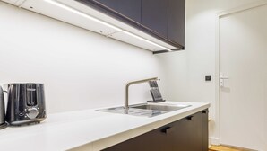 A modern kitchen with a white countertop, stainless steel appliances, and a built-in sink. - Cosy Apartment - 1br/4p - Near Champs-elysees (Paris)