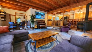 A cozy living room with a wooden ceiling, a television, a piano, and a fireplace.