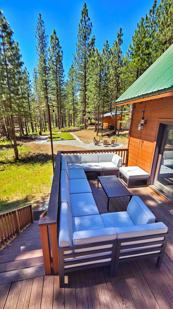 Una terraza con sofá y mesa integrados, rodeada por un bosque.