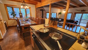 A cozy kitchen with a stove, pots, and a dining area with chairs and a table set for a meal.