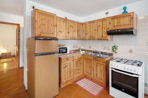 Cucina con mobili in legno, frigorifero, microonde, piano cottura a gas e lavello.
