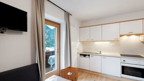A modern kitchen with white cabinets, a built-in oven, and a window overlooking a snowy mountain. - Apartment 'Pfaffingerhof Apt Piccolo Rabbit' with Mountain View, Shared Garden and Wi-Fi (Anterselva di Sotto BZ)
