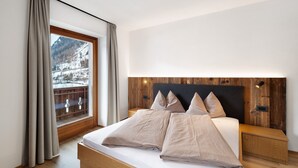 A bedroom with a large bed, wooden headboard, and a view of a snowy mountain. - Apartment 'Pfaffingerhof Apt Piccolo Rabbit' with Mountain View, Shared Garden and Wi-Fi (Anterselva di Sotto BZ)