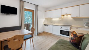A modern kitchen with white cabinets, a built-in oven, and a window with a view of trees. - Apartment 'Pfaffingerhof Apt Piccolo Rabbit' with Mountain View, Shared Garden and Wi-Fi (Anterselva di Sotto BZ)