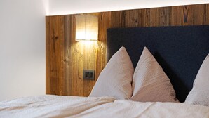 A bed with a headboard, pillows, and a wall-mounted light fixture.