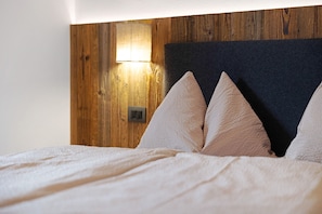 Un lit avec une tête de lit, des oreillers et un luminaire fixé au mur.