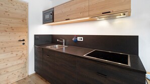 A modern kitchen with dark cabinetry, a stainless steel sink, and a microwave.