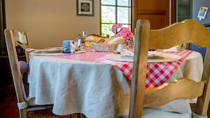 A dining table with a checkered tablecloth, a basket of bread, a mug, and a vase of flowers. - Bed and Breakfast 'Il Pellegrino' with Mountain Views, Shared Garden and Wi-Fi (La Place)