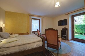 Ein Schlafzimmer mit Bett, Sessel, Fernseher und Blick ins Freie.