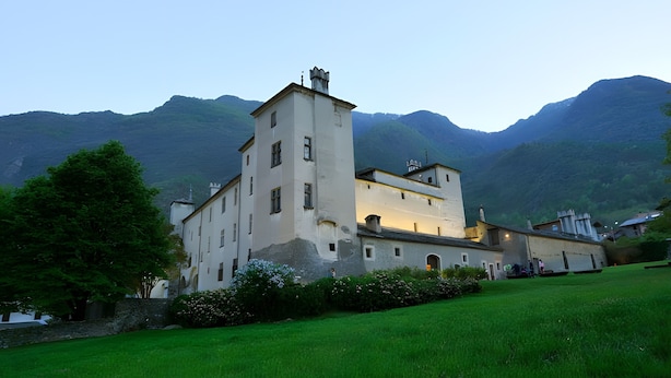 A large building with multiple windows and a tower, surrounded by a grassy area and mountains in the background. - Bed and Breakfast 'Il Pellegrino' with Mountain Views, Shared Garden and Wi-Fi (La Place)
