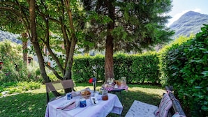 An outdoor dining area with a table set for two, surrounded by greenery and a mountain view. - Bed and Breakfast 'Il Pellegrino' with Mountain Views, Shared Garden and Wi-Fi (La Place)