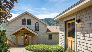 A two-story house with a covered porch, a front door, and a small garden area. - Wapato Point Escape: Private Hot Tub • Walk to Beach • Lake Views (Manson)