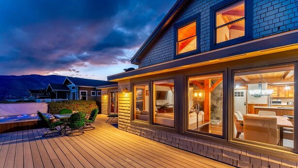 A modern house with large windows, a deck, and a mountain view. - Wapato Point Escape: Private Hot Tub • Walk to Beach • Lake Views (Manson)