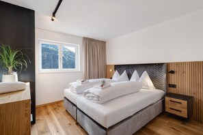 A modern bedroom with a large bed, bedside tables, a potted plant, and a window with a view. - Apartment 'Paradeis Apartments A20' with Mountain View, Balcony and Wi-Fi (Mühlbach)