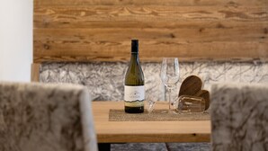 A wooden table with a wine bottle and glasses, set against a wooden wall. - Apartment 'Paradeis Apartments A20' with Mountain View, Balcony and Wi-Fi (Mühlbach)