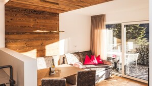 A modern interior with a dining area, a sofa with red cushions, and a wooden ceiling. - Apartment 'Paradeis Apartments A20' with Mountain View, Balcony and Wi-Fi (Mühlbach)
