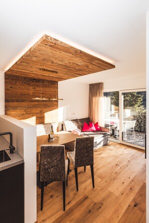A modern interior with a dining area, a sofa with red cushions, and a wooden ceiling.
