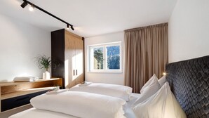 A bedroom with a bed, bedside tables, a window, curtains, and a plant. - Apartment 'Paradeis Apartments A20' with Mountain View, Balcony and Wi-Fi (Mühlbach)