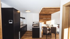 A modern kitchen with a built-in island, wooden flooring, and a dining area with chairs. - Apartment 'Paradeis Apartments A20' with Mountain View, Balcony and Wi-Fi (Mühlbach)