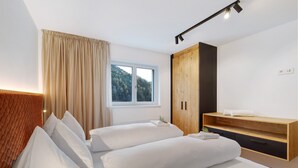 A bedroom with two beds, a window with a view of trees, a wooden wardrobe, and a bedside table with a plant. - Apartment 'Paradeis Apartments A19' with Mountain View, Private Terrace and Wi-Fi (Mühlbach)