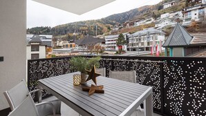 A balcony with a table and chairs, a decorative star, and a potted plant. - Apartment 'Paradeis Apartments A18' with Mountain View, Private Terrace and Wi-Fi (Mühlbach)