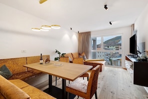 A modern living room with a wooden dining table, sofas, and a large window with a city view.