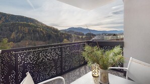 A balcony with a view of a forested mountain range, a decorative plant, and a chair. - Apartment 'Paradeis Apartments A17' with Mountain View, Balcony and Wi-Fi (Mühlbach)