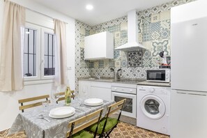 Een kleine keuken met een eethoek, een wasmachine en een magnetron.