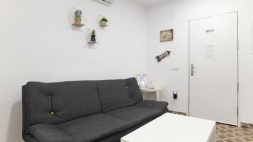 A room with a grey sofa, a white table, and a door with a sign.