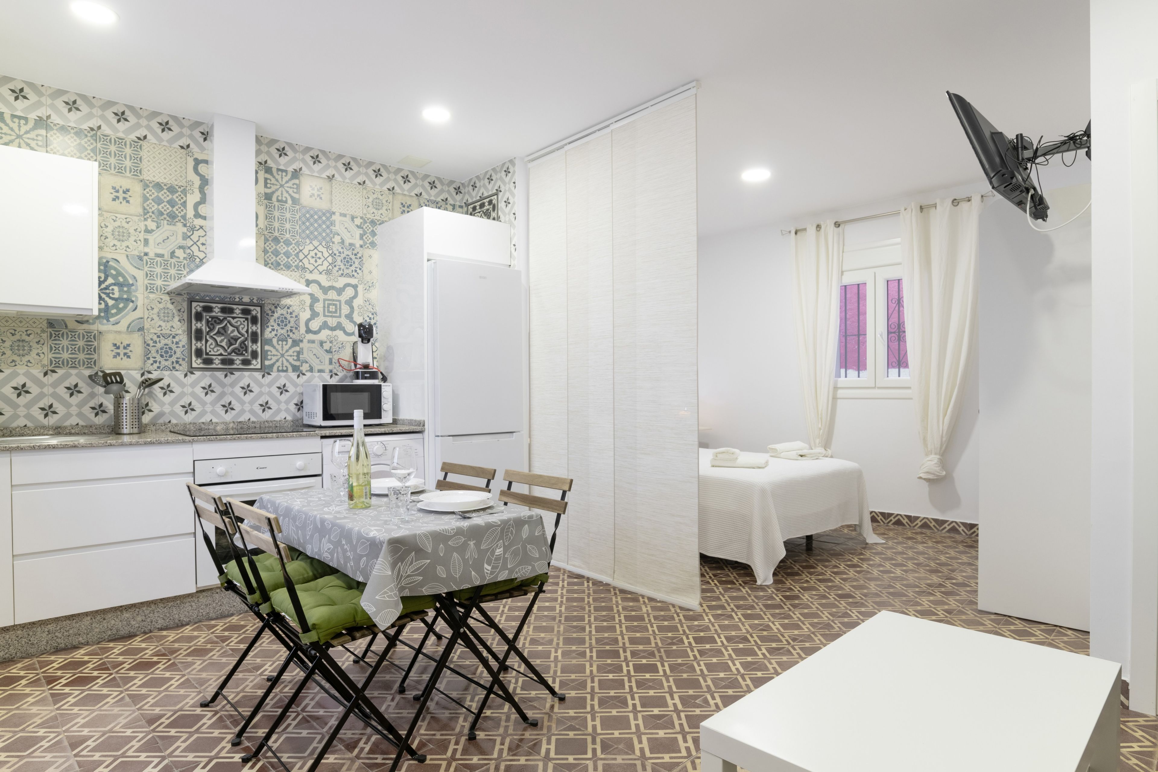 A compact kitchen with a microwave, a refrigerator, and a dining area with a table and chairs.